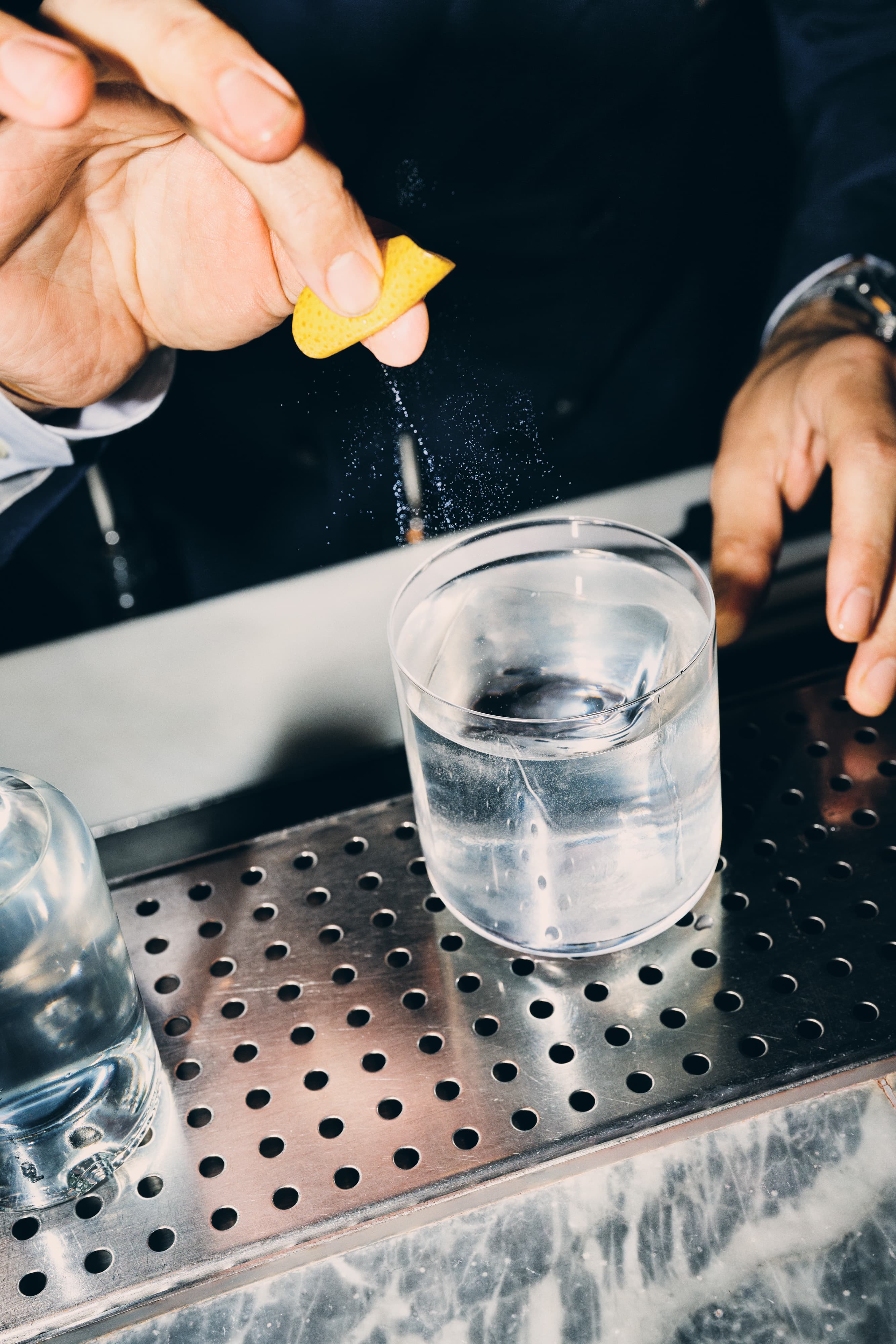 A hand squeezing a lemon into a cocktail