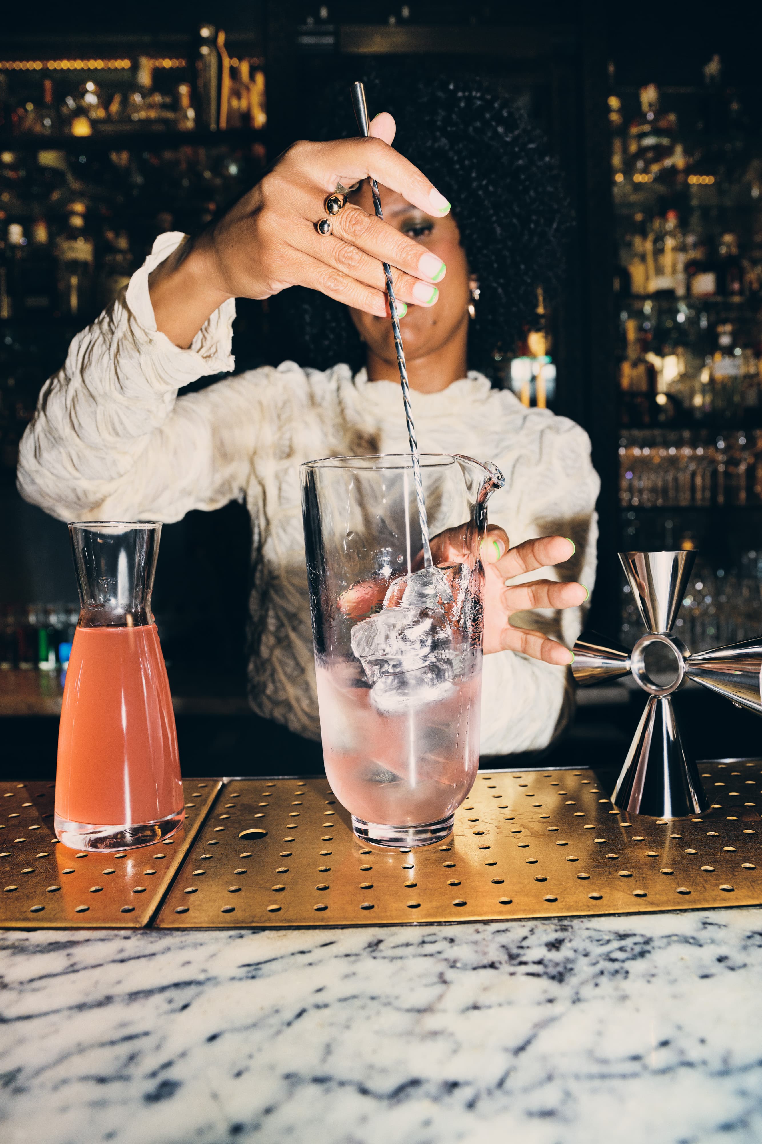 Jenna Ba mixing Tanqueray No. Ten and grapefruit juice in a large mixing glass.