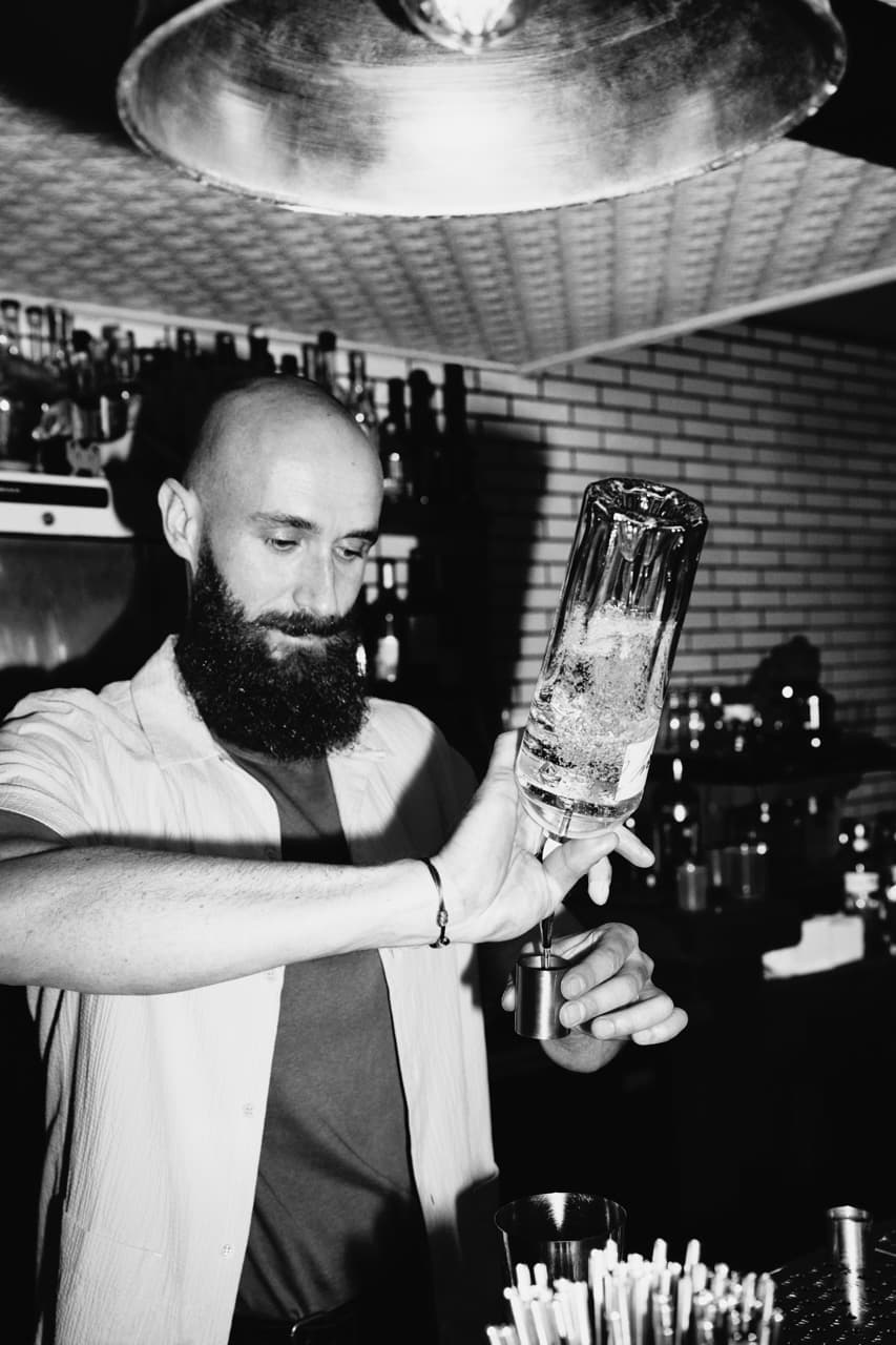 A person pouring Tanqueray No. Ten into a jigger.