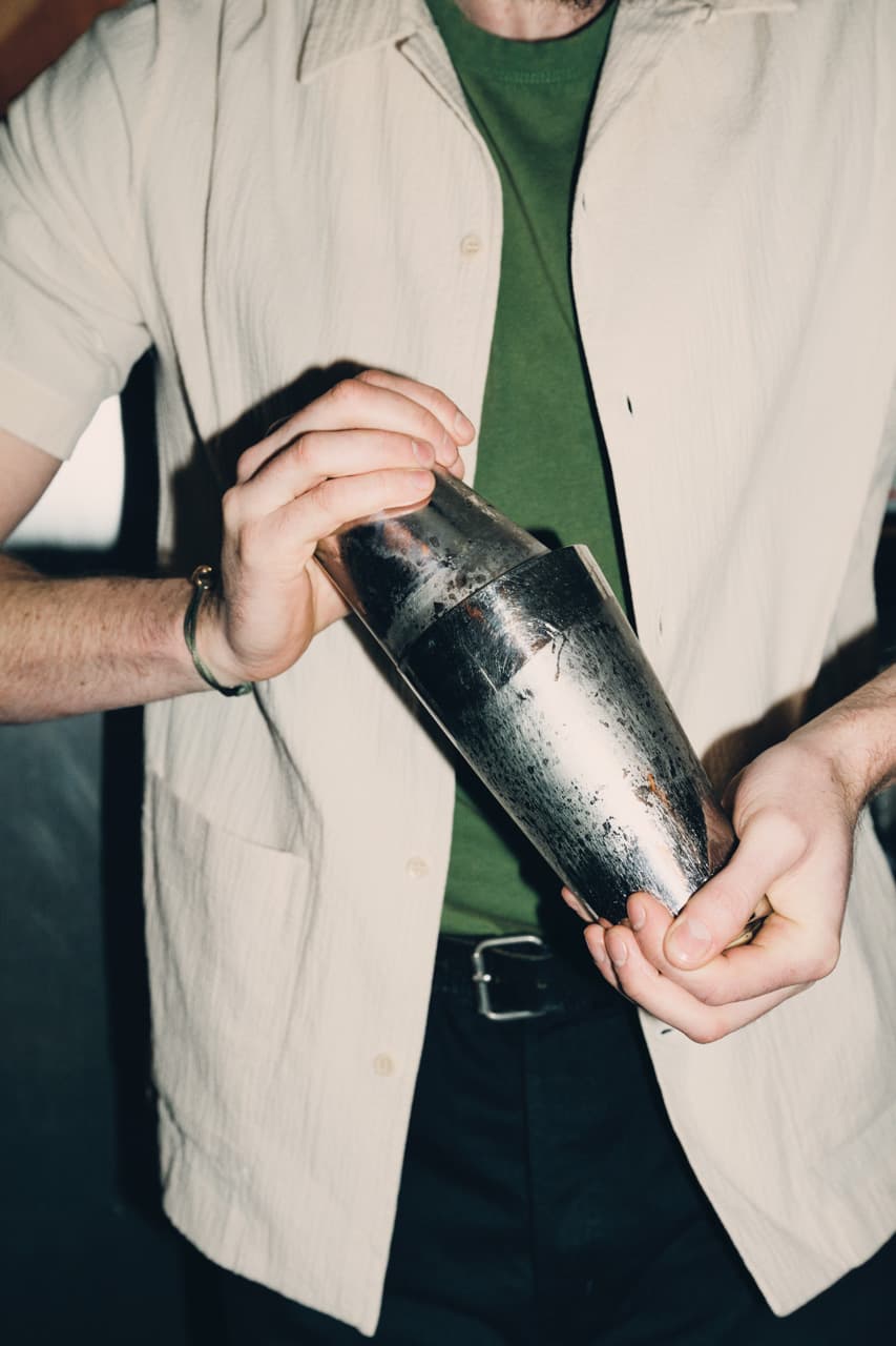 Two hands holding a chilled cocktail shaker.