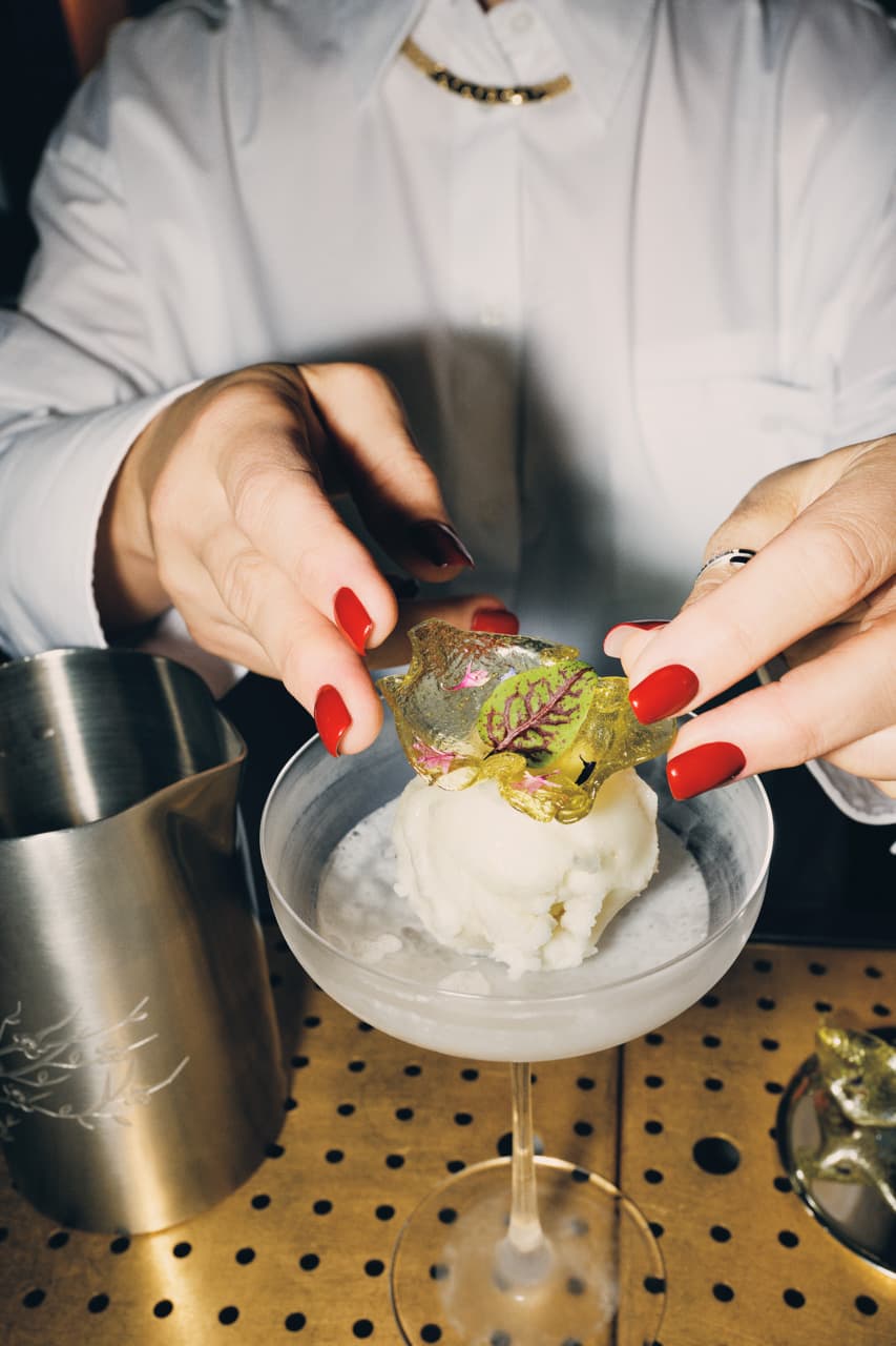 A garnish is placed on sorbet in a cocktail glass.