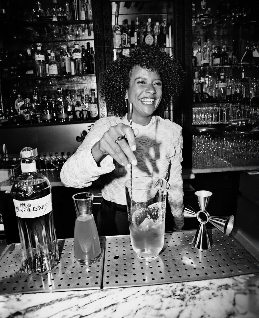 Jenna Ba smiling and mixing a cocktail.